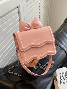 Pink mini crossbody bag with a 3D bow, wavy flap design, and silver chain strap