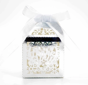 Close-up of silver laser-cut wedding favor box with heart design and thank you tag