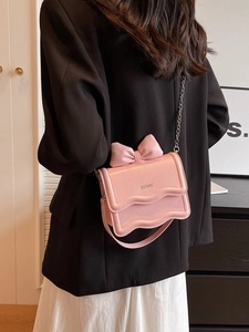 Chic light pink bow cross-body mini bag with silver chain strap shown on a model