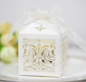 Détail d'une boîte à dragées blanche découpée au laser avec motif évidé et ruban de soie