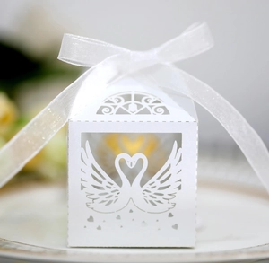 Detailed view of laser-cut white swan wedding favor box with an elegant organza ribbon