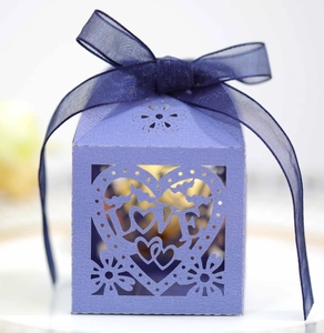 Macro d'une boîte cadeau violette découpée au laser avec motif LOVE et ruban bleu