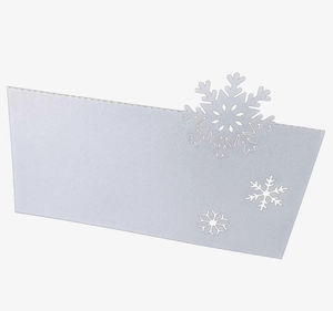 Detailed view of white laser-cut card featuring intricate snowflake patterns for table settings