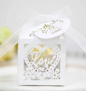 Macro detail of laser-cut 'Love' wedding favor box with white ribbon and thank you tag