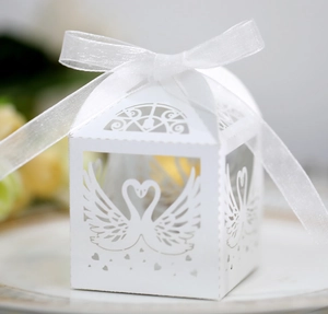 Detailed laser-cut white wedding favor box featuring swan heart pattern and organza bow