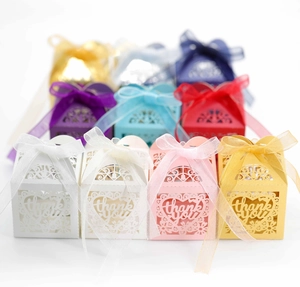 Close-up of laser-cut heart favor boxes with thank you text and silk ribbons in various colors