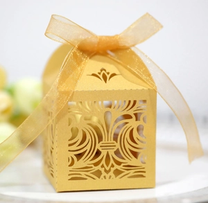 Gros plan d'une boîte à bonbons dorée ajourée avec texture perlée et nœud en organza