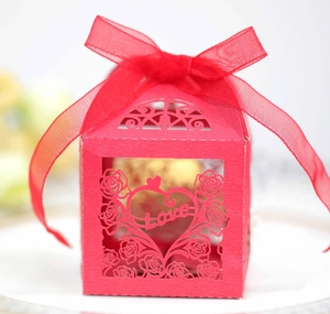 Macro shot of red laser-cut wedding favor box featuring rose patterns and Love engraving