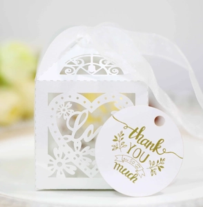 Detail of laser-cut heart favor box with white ribbon and gold thank you tag