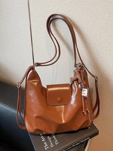 Vintage brown leather hobo shoulder bag with glossy finish and metal charm detail