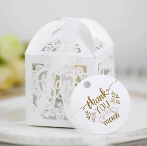 Detailed view of white laser cut heart candy box with ribbon and gold foil thank you tag