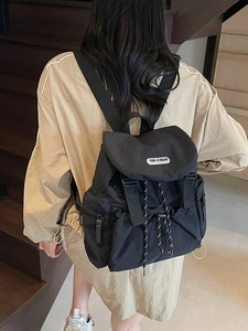 Fashionable black nylon backpack for women featuring a drawstring closure and buckle flap