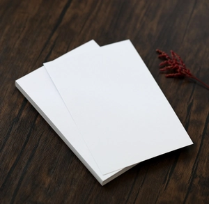 Close-up of stacked white pearlescent paper cards on a textured walnut wood surface
