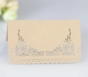 Elegant champagne gold laser-cut lace wedding place card on a soft grey background