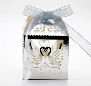 Detail view of silver laser-cut wedding favor box with swan heart pattern and ribbon bow