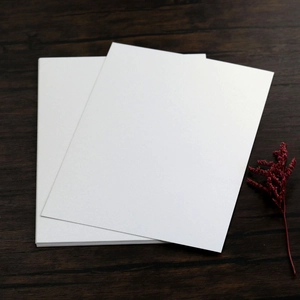 Elegant white pearlescent wedding invitation cards set on a dark wood background