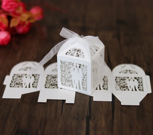 Detail of white laser-cut favor box with bride and groom silhouette and ribbon