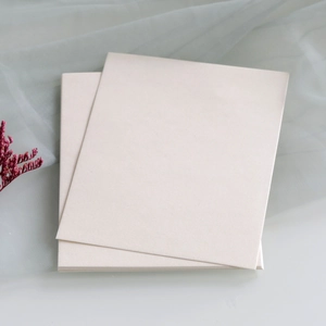 Close-up of blank cream wedding invitation cards with textured pearlescent finish