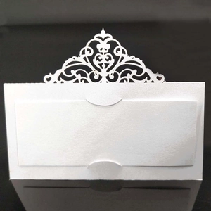 Macro shot of white laser-cut seat card with elegant hollow pattern for wedding decor