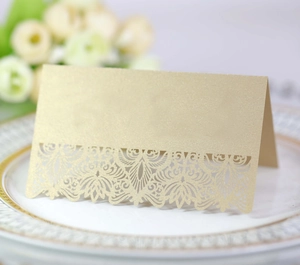 Elegant champagne gold laser-cut lace wedding place card on a gold-rimmed white plate