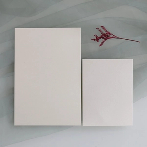 Macro shot of blank ivory pearl paper cards for wedding invitations on blue gauze