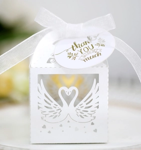 Detail of white laser-cut swan wedding candy box with thank you tag and ribbon