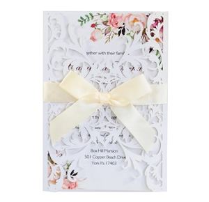 Detail of laser-cut wedding invitation with white floral lace and pink flower inner sheet