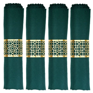 Set of four gold metal napkin rings with hollow geometric patterns and green cloth napkins