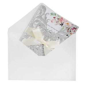 Macro detail of laser-cut rose glitter invitation with a cream satin bow and floral inner card