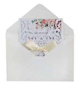 Detail of laser-cut rose floral wedding invitation with satin bow and floral inner card
