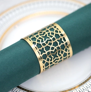 Macro shot of gold hollowed-out napkin ring with intricate pattern on green fabric