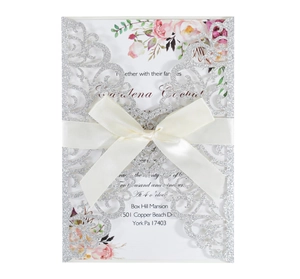 Elegant laser cut silver glitter wedding invitation with white satin bow and floral insert