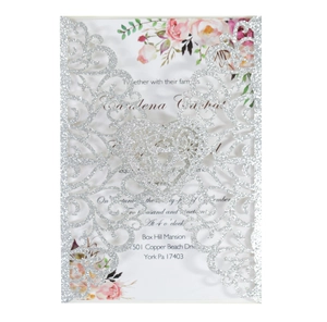 Detail of silver glitter laser-cut wedding invitation featuring a romantic heart pattern