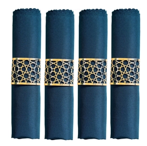 Close-up of four navy fabric napkins with gold geometric star cut-out metal napkin rings