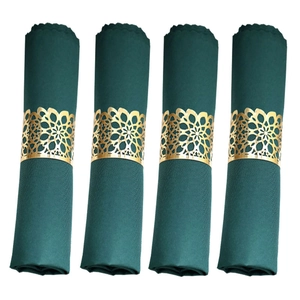 Close-up of four dark green fabric napkins with ornate gold mandala metal napkin rings