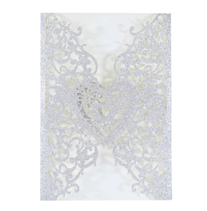 Macro detail of laser-cut heart hollow pattern on silver glitter wedding invitation cover