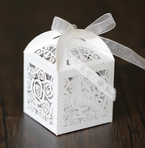 Detailed laser-cut rose pattern on white wedding favor box with organza ribbon