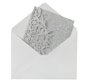 Detail of silver glitter laser-cut floral wedding invitation with matching white envelope