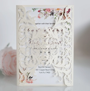 Detail of laser cut wedding invitation with cream white floral pattern and rose inner card
