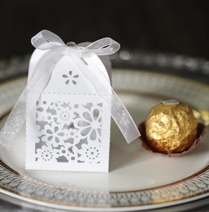 Detail of white laser-cut hollow gift box with floral pattern and white ribbon bow
