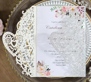 Macro detail of laser-cut wedding invitation with hollow floral pattern and silver glitter