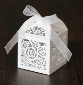 Detail of white laser-cut rose hollow favor box with elegant chiffon ribbon bow