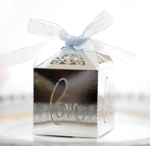 Close-up of silver hollow Love favor box with light blue ribbon on elegant white porcelain