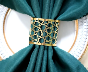 Close-up of geometric star pattern on a golden metal napkin ring with dark green fabric