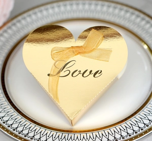 Macro shot of a golden heart-shaped favor box with Love script and matching ribbon bow