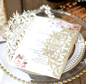 Intricate laser-cut wedding invitations with gold glitter and elegant floral inner pages