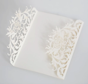 Intricate laser-cut white wedding invitation with elegant rose patterns and lace details