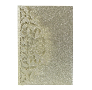Detail of champagne gold glitter card with intricate laser-cut floral patterns for invitations