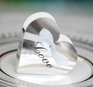 Close-up of heart-shaped silver gift box with Love hollow design and white organza ribbon