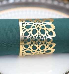 Detailed macro view of laser-cut gold napkin ring with hollow geometric flower patterns